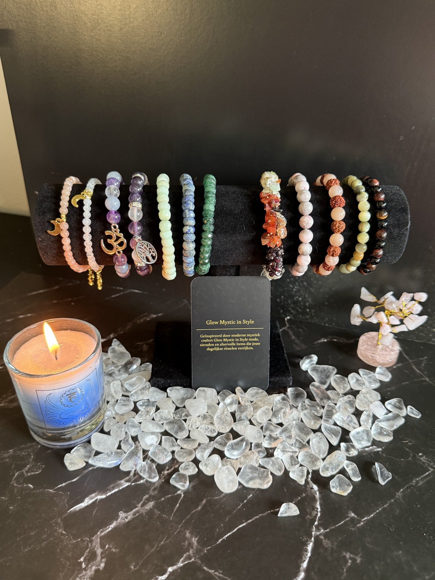 armbanden standaard met diverse edelsteenarmbanden met op de achtergrond kristal steentjes en een kaarsje