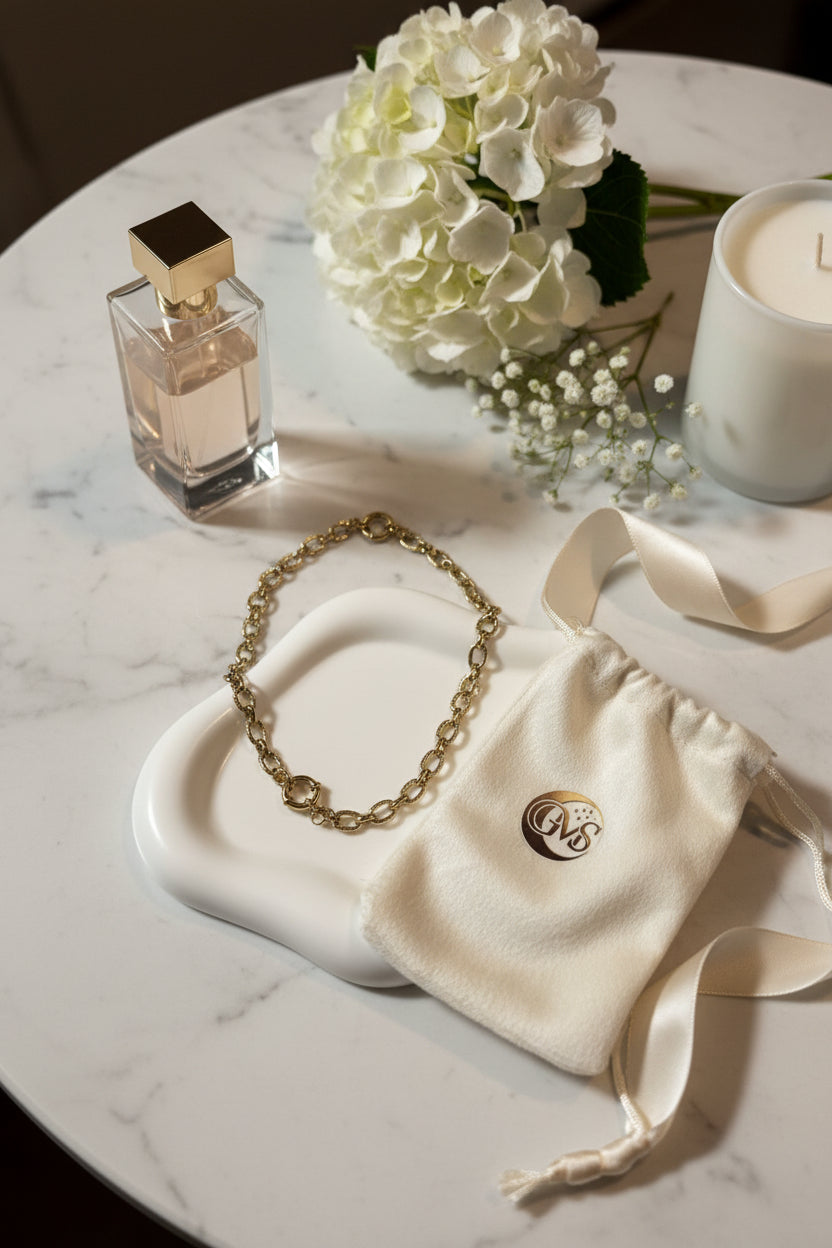 Luxe gouden schakelketting van roestvrij staal op decoratieve schaal naast sieradenzakje van Glow Mystic in Style.