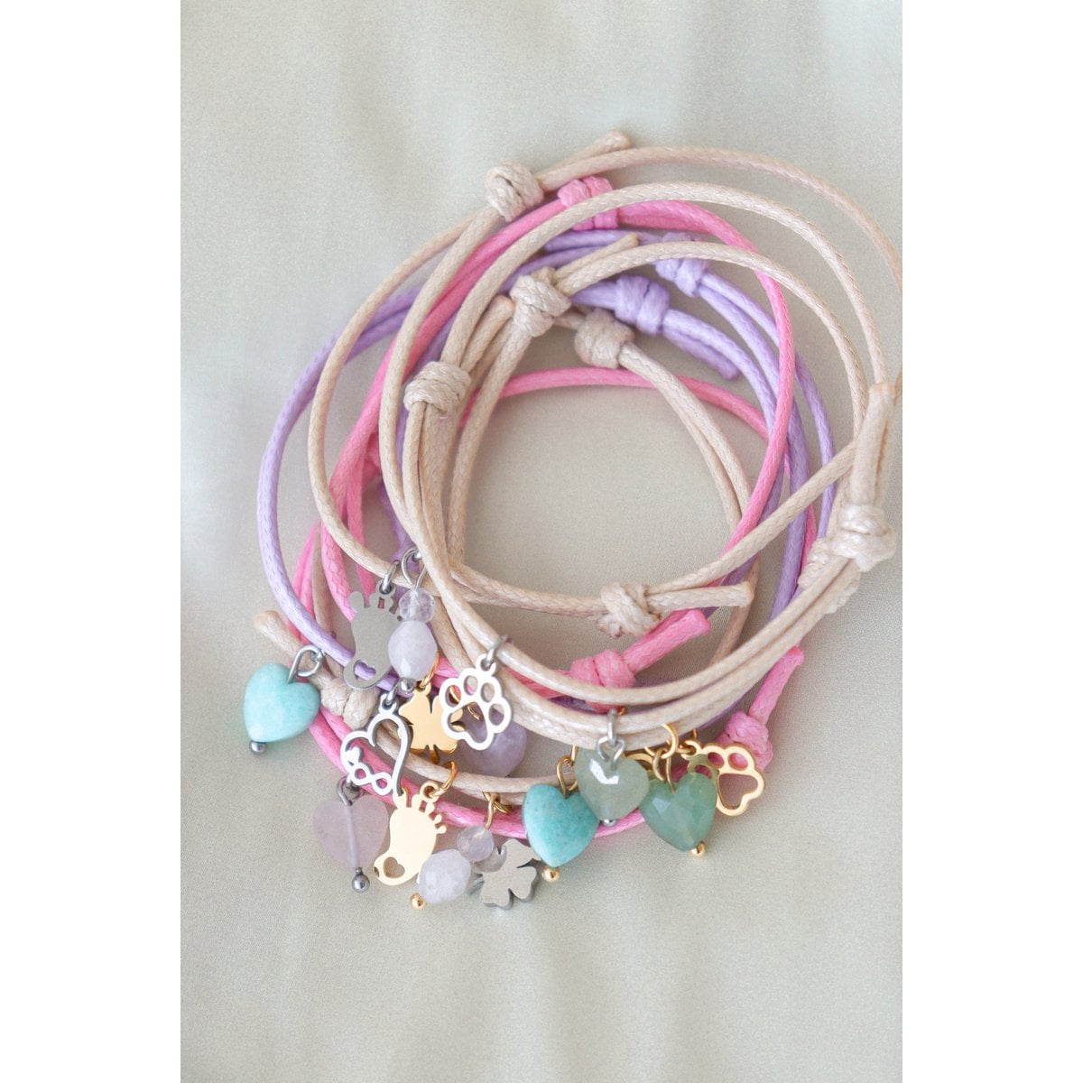 "Close-up detailfoto van de armbandjes aan een sieradenhouder, focus op de verfijnde goudkleurige bedels en het vakmanschap van de schuifknopen."