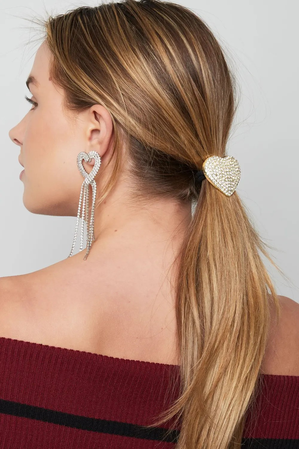 Model van de achterkant met blond haar in een lage paardenstaart, vastgezet met het luxe gouden strass hart haarelastiek shimmer of love van Glow Mystic in Style.