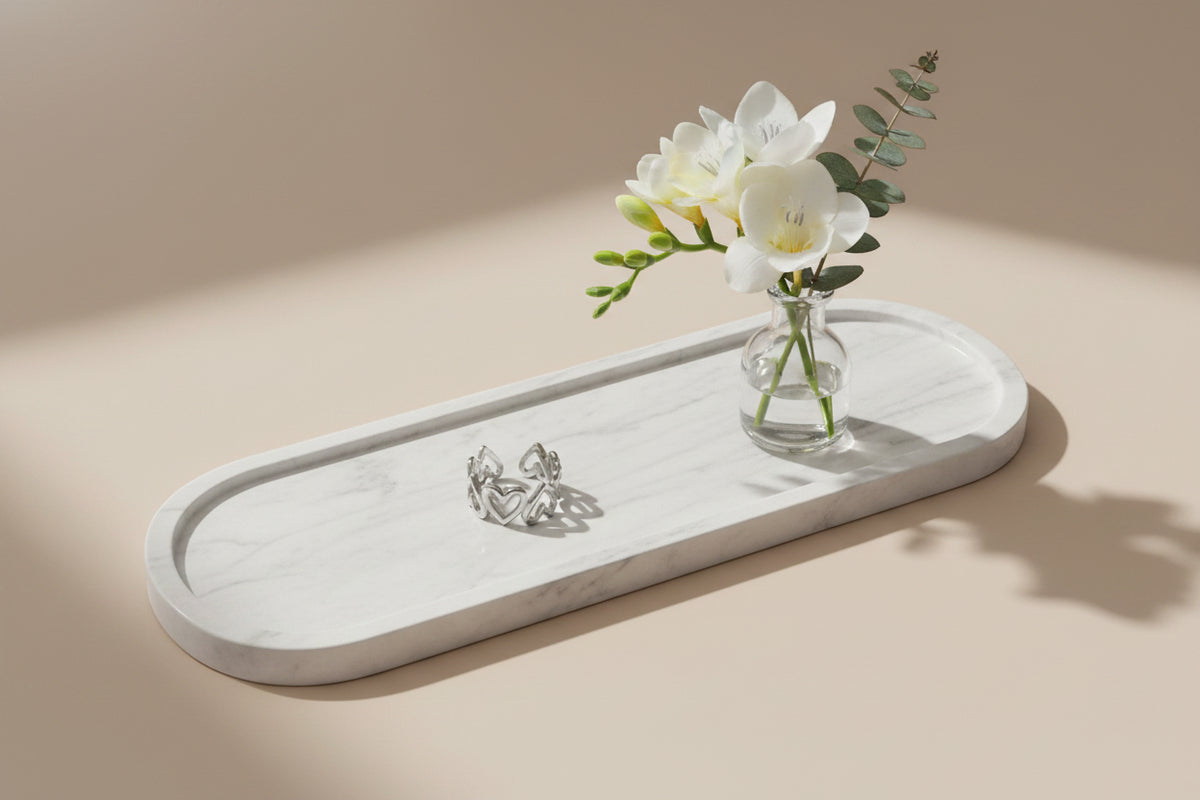 Zilveren open ring met hartjes op een ovale marmeren tray, gedecoreerd met een glazen vaasje met witte freesia's en eucalytus.