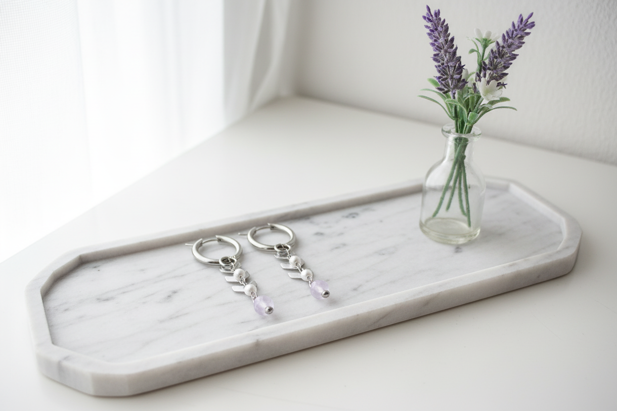 Dames oorbellen jade parels herringbone detail op een marmeren schaal met een vaasje bloemen gepresenteerd.