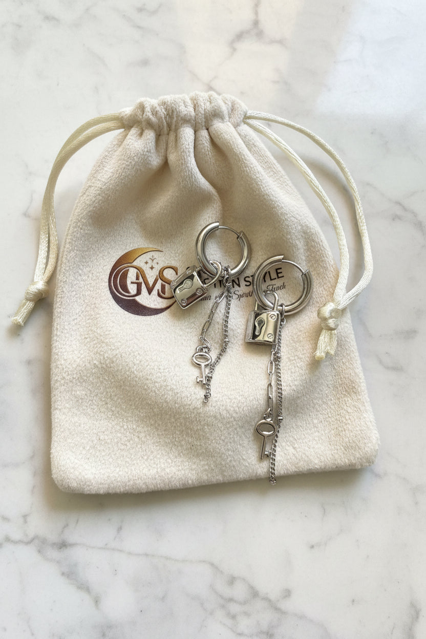 Luxe zilveren slotjes oorbellen liggend op een beige Glow Mystic in Style sieradenzakje op een elegante wit-grijze marmeren plaat.