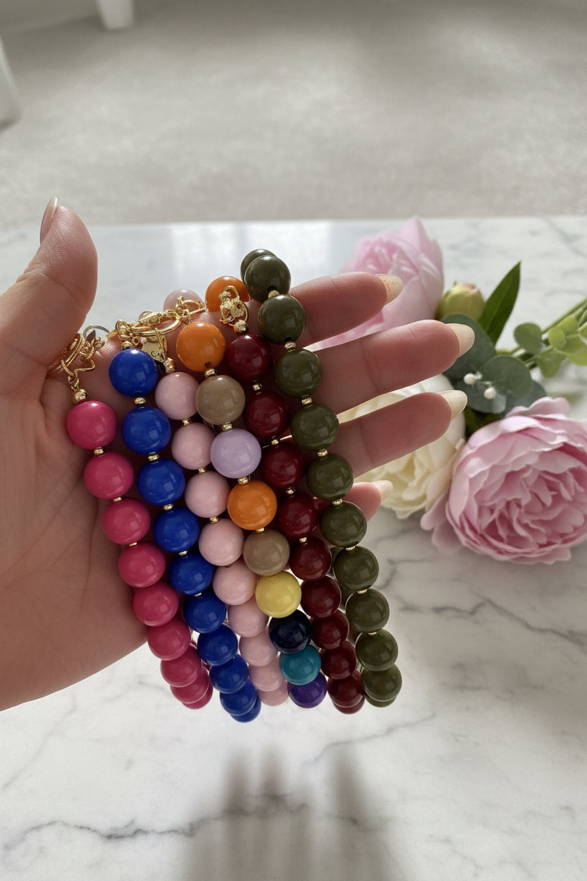 Collectieoverzicht van handgemaakte phone charms door Glow Mystic in Style in diverse trendy kleuren zoals koningsblauw, bordeauxrood, fuchsia roze, olijfgroen en okergeel, voorzien van luxe gouden accenten.