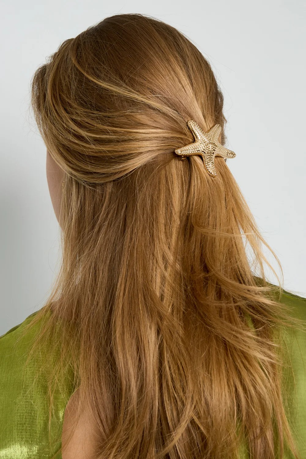 Model van de achterkant met lichtbruin haar in een half-up look, versierd met een gouden metalen zeester haarschuif van Glow Mystic in Style.