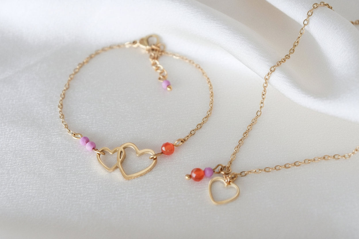 Gouden hartjesketting met edelstenen, gefotografeerd op een wit satijnen kleed.