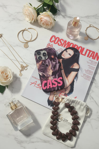 Bruin hartjes telefoonkoord naast smartphone op Cosmopolitan magazine met parfum, sieraden en Glow Mystic in Style sieradenzakje.