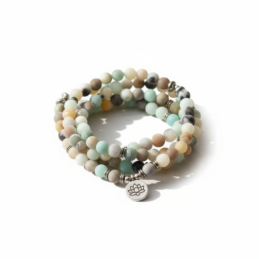 close-up van amazoniet mala armband en ketting met lotus bedel op marmeren plaat met kaarsen en decoratie, spiritueel sieraad voor meditatie en rust