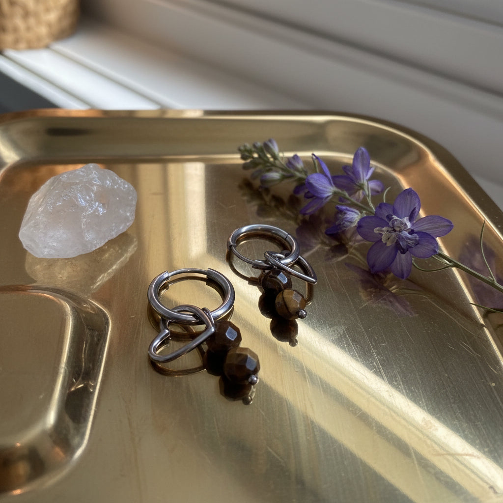 Glow Mystic in Style zilveren charm oorbellen met open hartje en bruine kralen op gouden tray