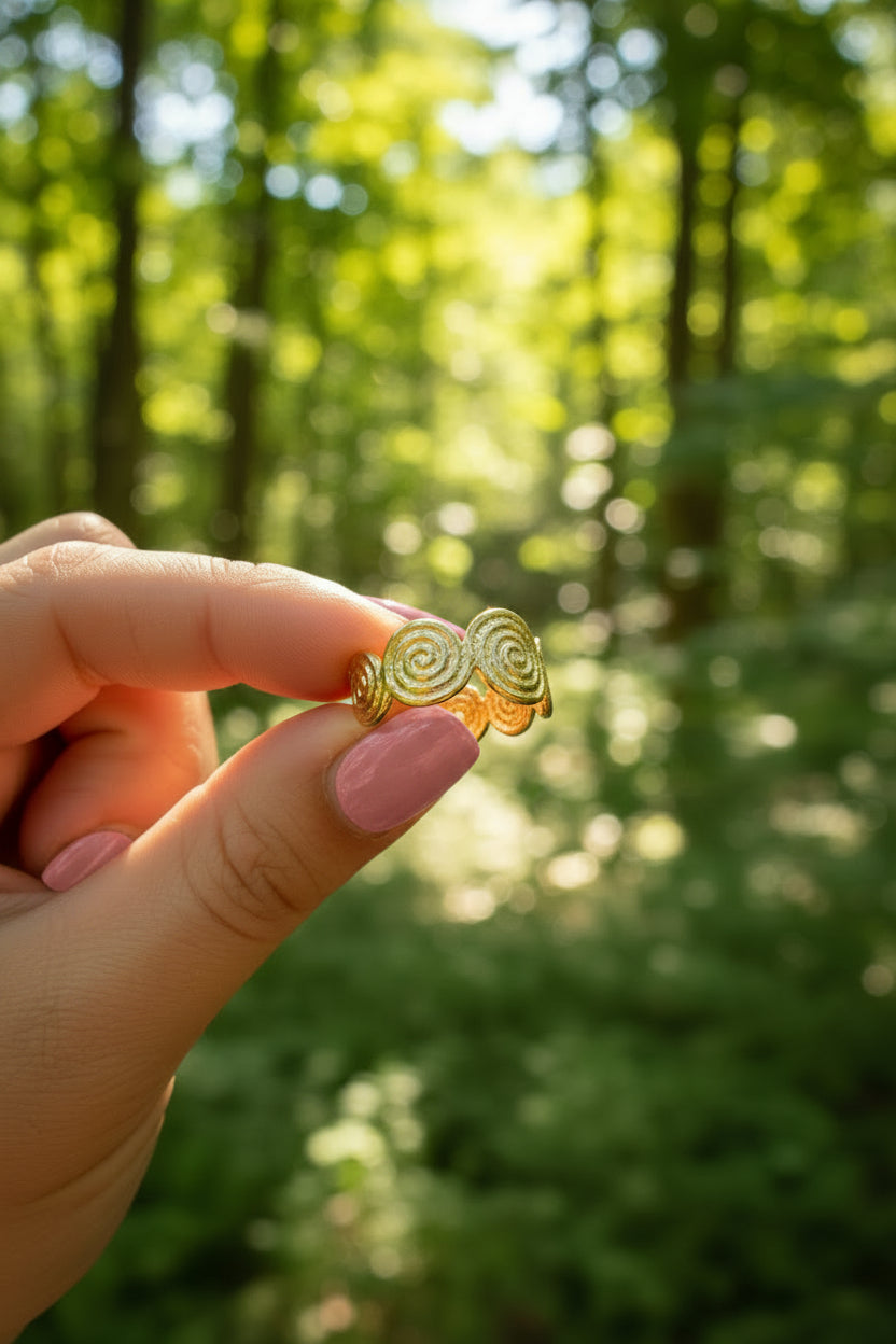 Gouden Soleil ring vastgehouden tegen een dromerige, zonnige groene bosachtergrond met natuurlijke belichting