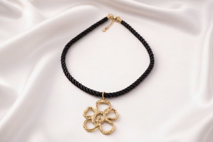 Zwarte gedraaide ketting met grote gouden bloem pendant.