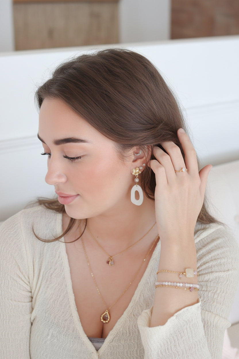 Model draagt goudkleurige oorbellen met parelmoer look – moderne sieradenstijl