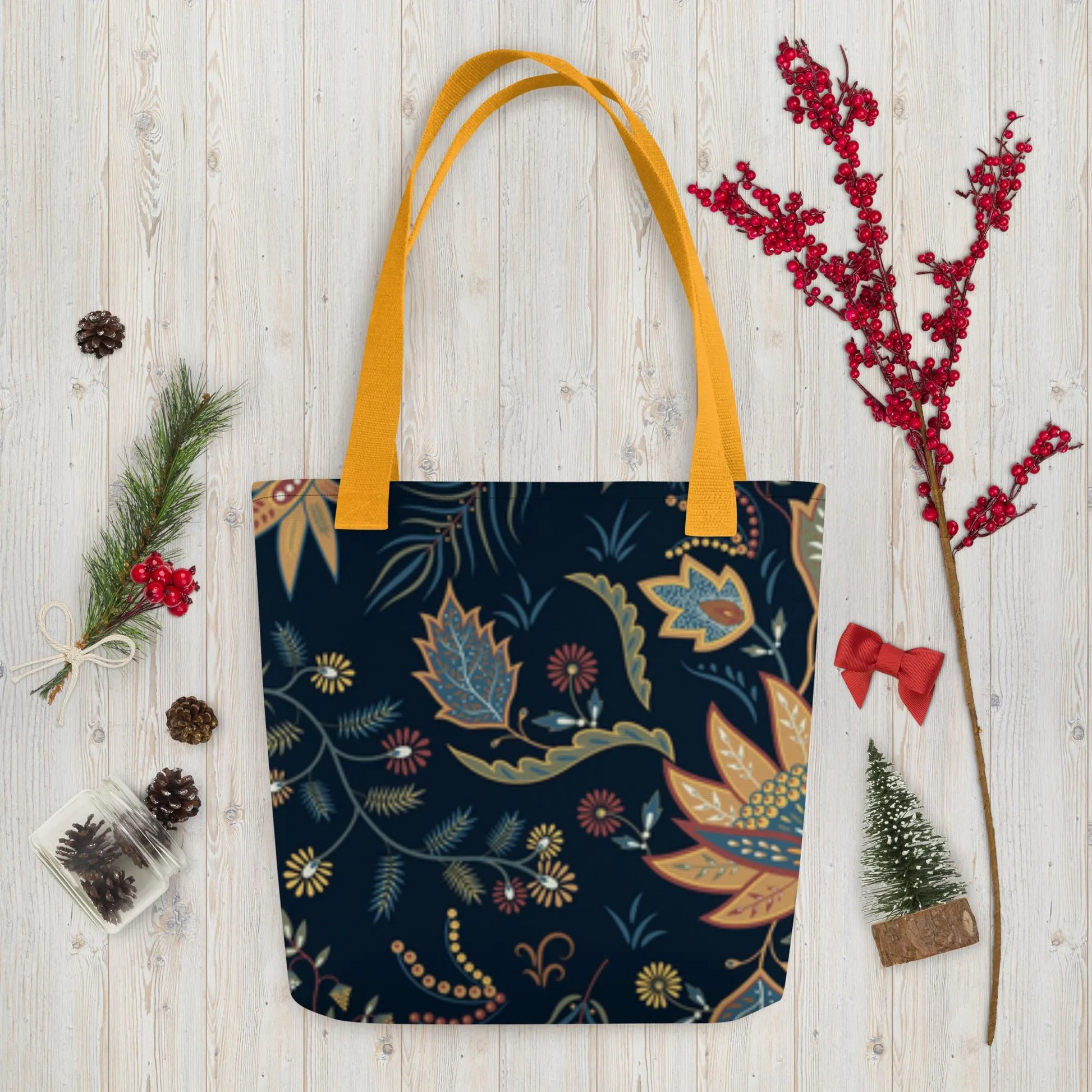 Autumn Floral Tote Bag with dark background and colorful fall leaves design with mustard yellow handles on wooden surface with seasonal decorations