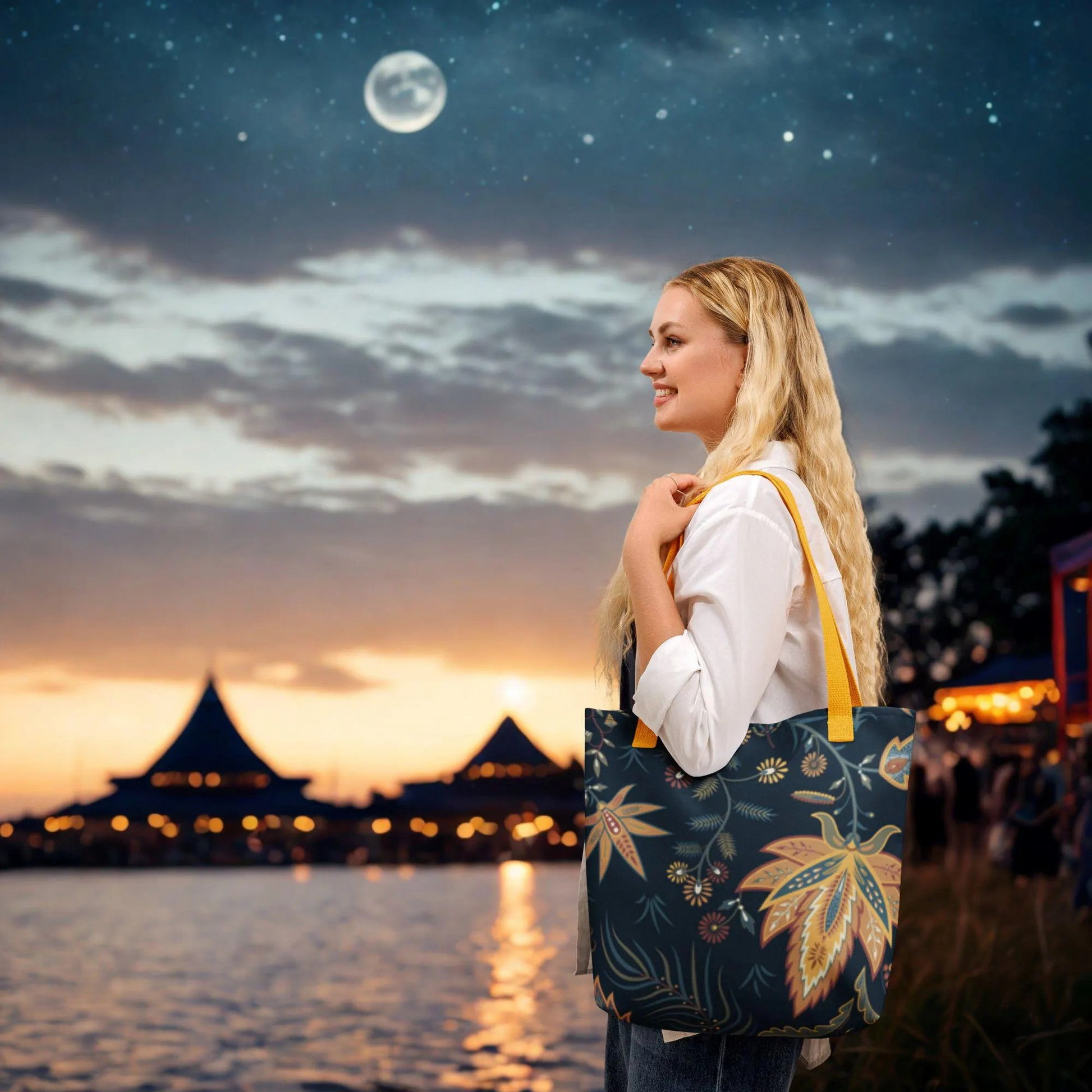 Woman carrying Autumn Floral Tote Bag with yellow handles and fall-themed design by waterfront at sunset