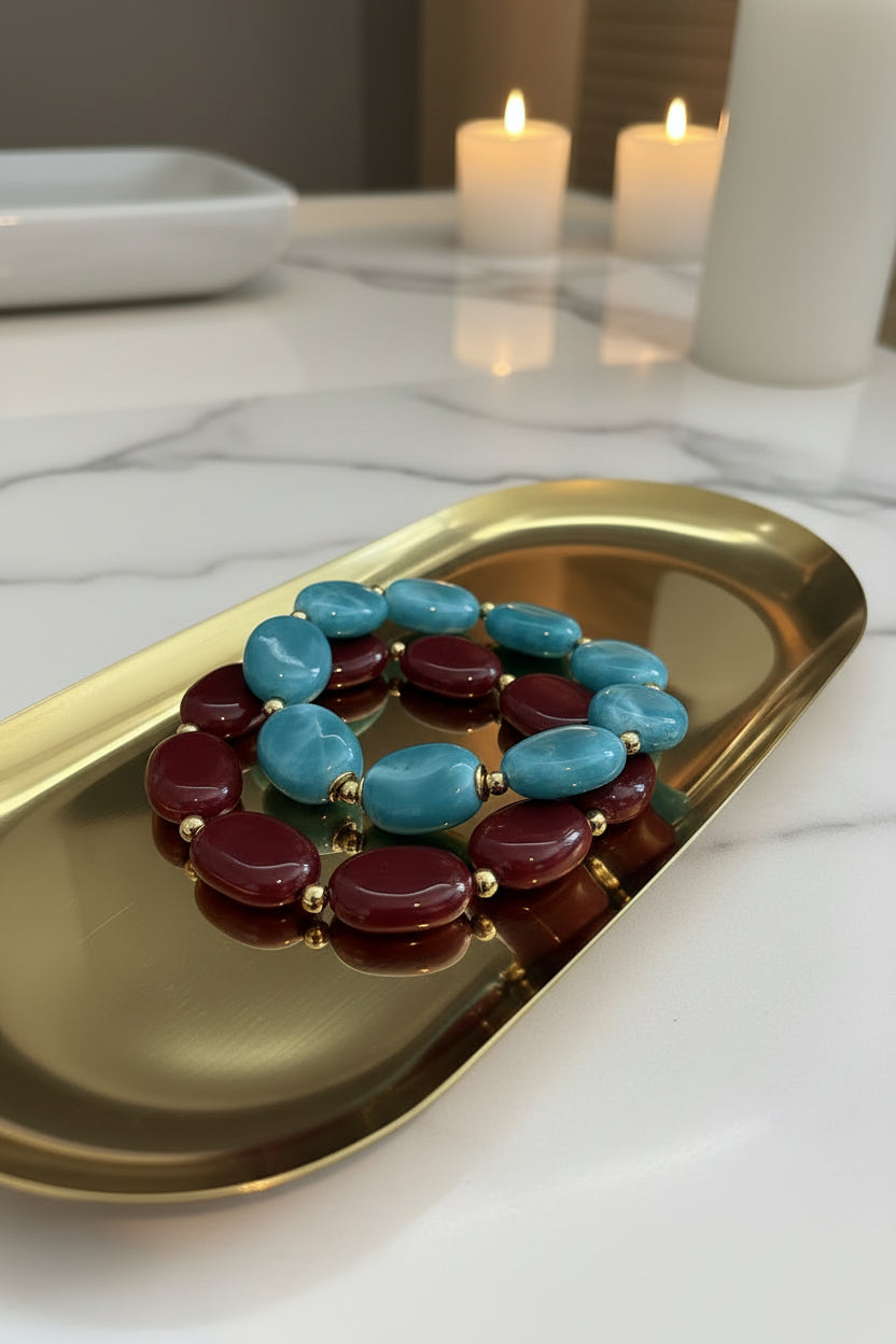 Detail van Glow Mystic in Style chunky acryl armbanden met gouden tussenkralen op een gouden schaal en een marmeren achtergrond.