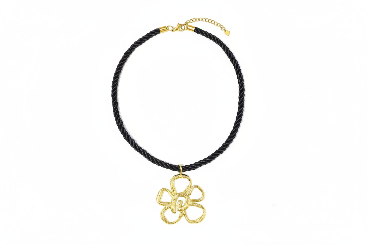 Zwarte koordketting met grote gouden bloemhanger.