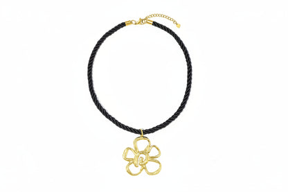 Zwarte koordketting met grote gouden bloemhanger.