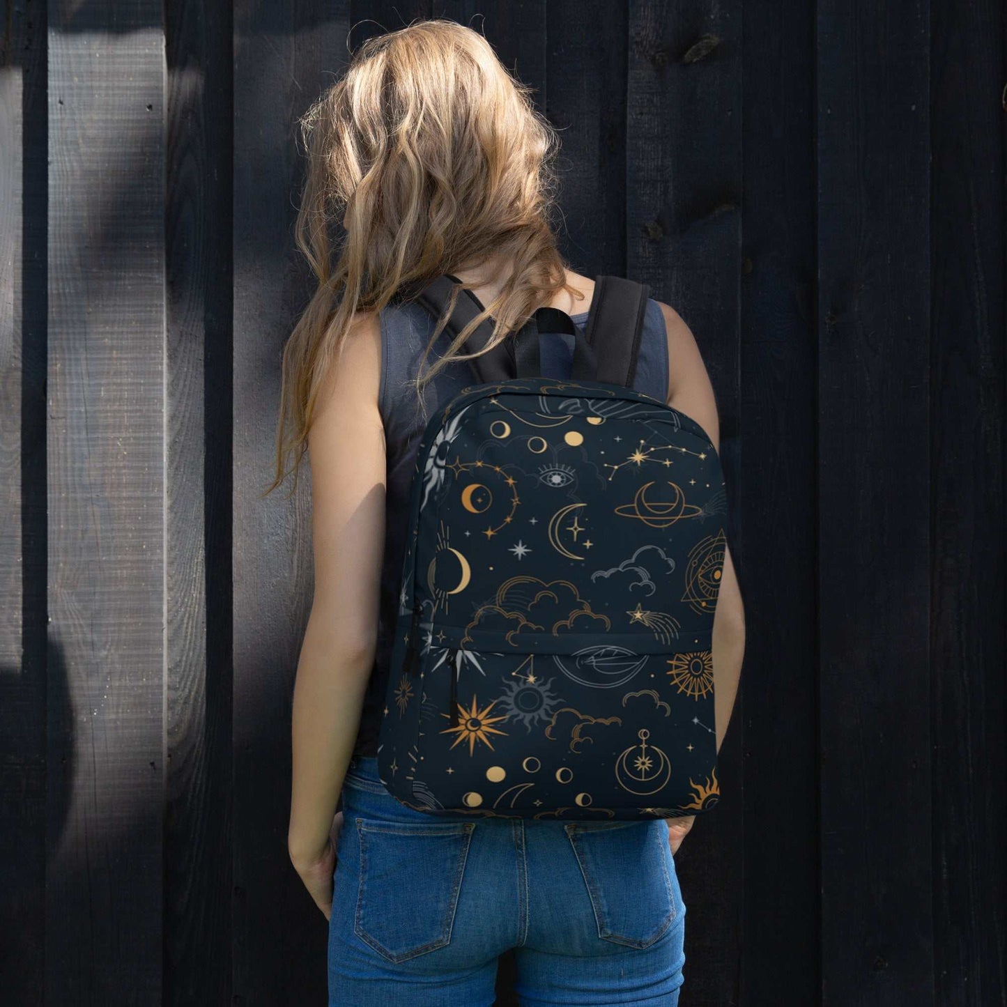 Woman wearing Mystic Moons and Stars Backpack with celestial moon and star patterns against dark wooden background