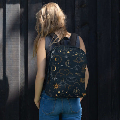 Woman wearing Mystic Moons and Stars Backpack with celestial moon and star patterns against dark wooden background