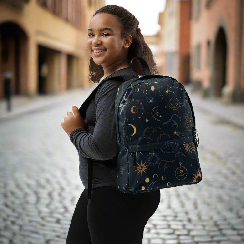 Young woman wearing a Mystic Moons and Stars Backpack with celestial moon and star design on a city street