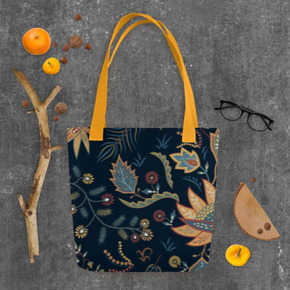 Autumn Floral Tote Bag with navy background and warm floral patterns, featuring sturdy orange handles on gray surface with seasonal decor.