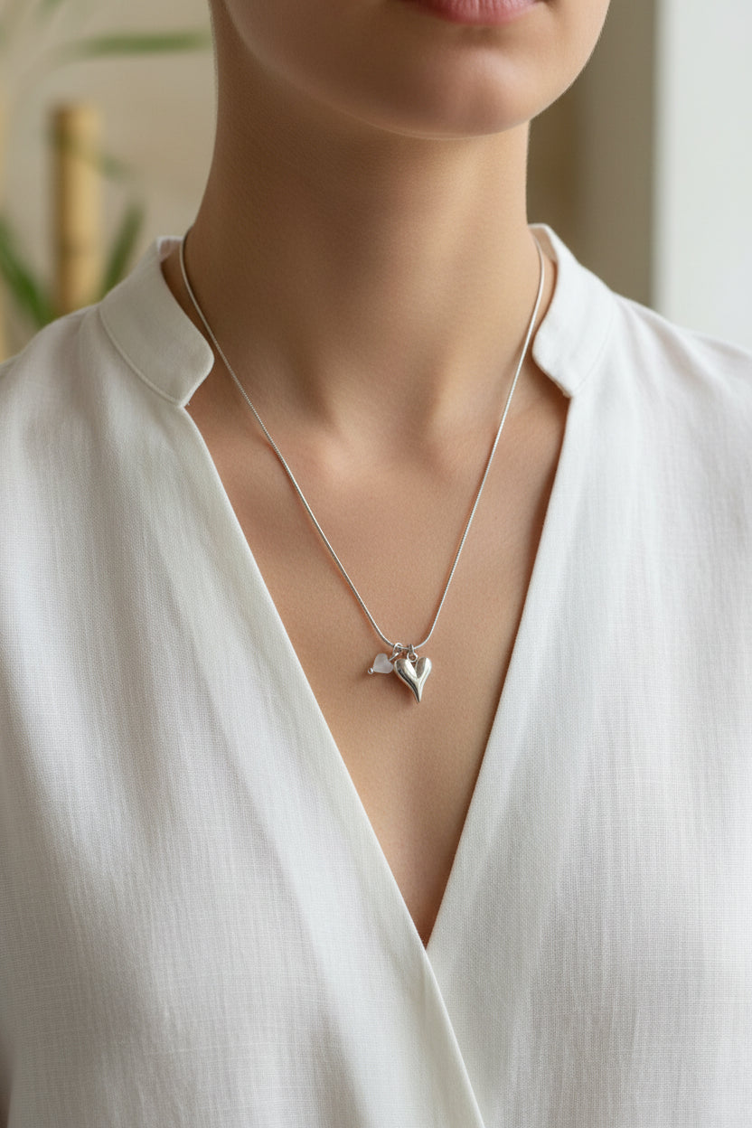 Zilveren hartjes ketting gedragen door model met elegante blouse