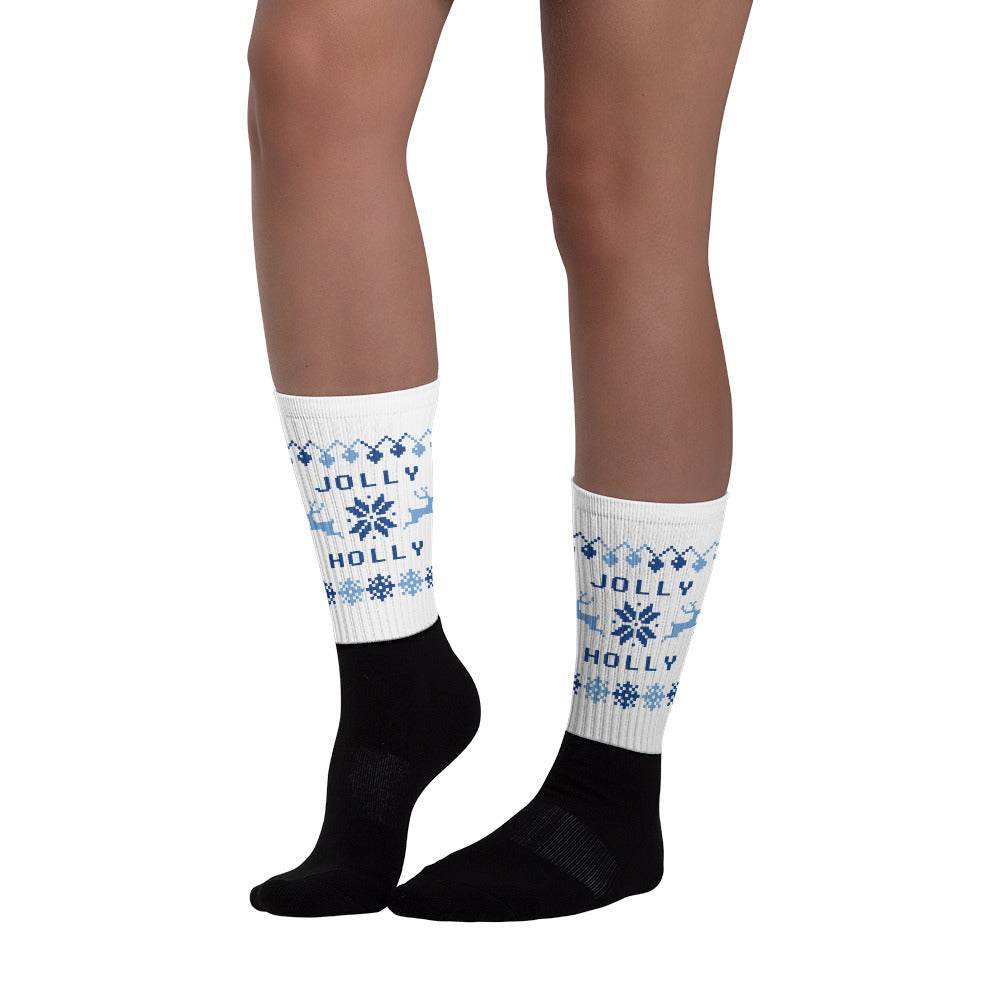 Pair of black and white Christmas socks with blue snowflake pattern and "Holly Jolly" lettering worn on legs