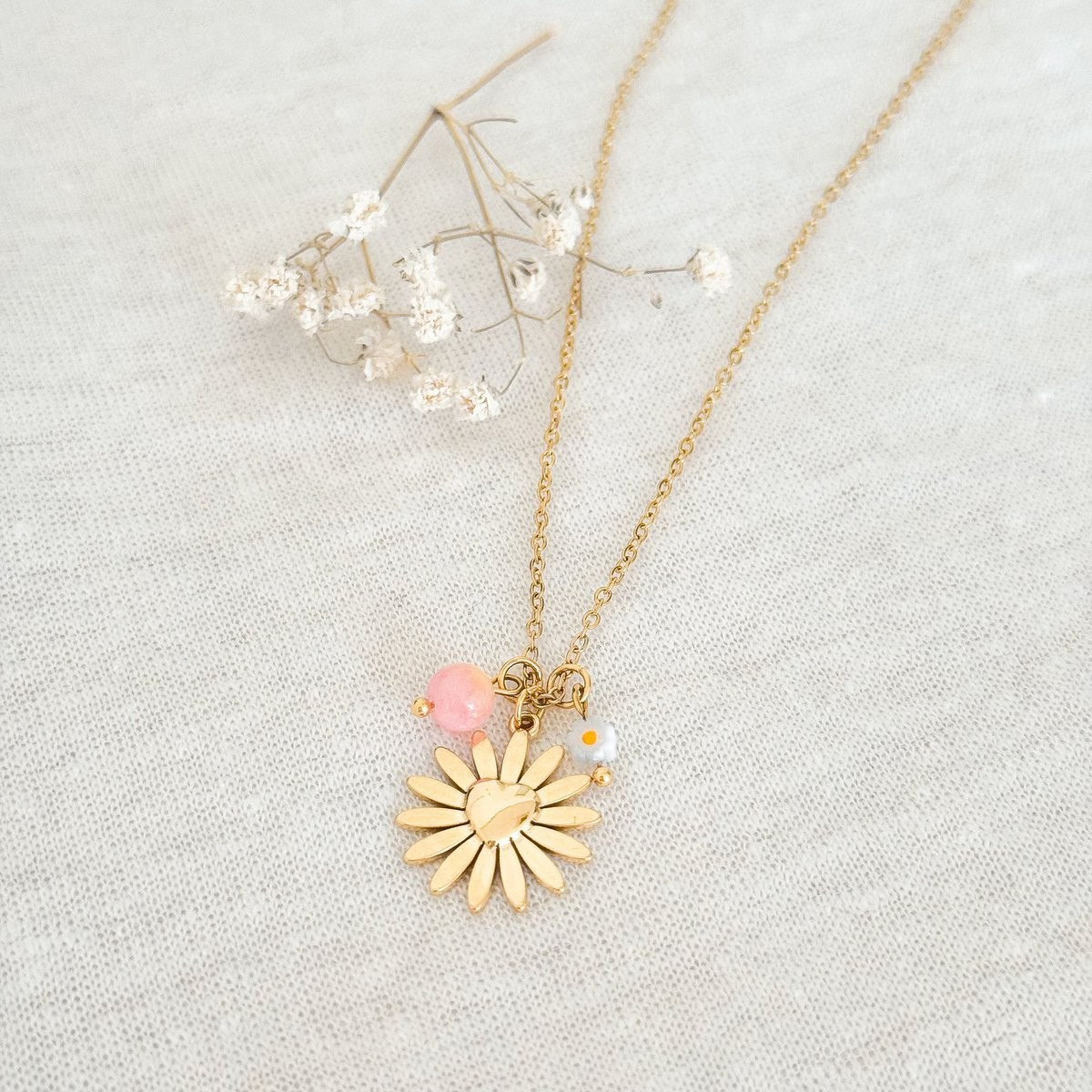 Gouden damesketting RVS met bloem hangers en rozenkwarts edelsteen op elegante achtergrond