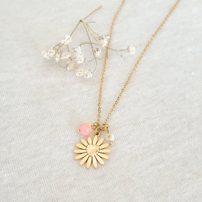 Gouden damesketting RVS met bloem hangers en rozenkwarts edelsteen op elegante achtergrond