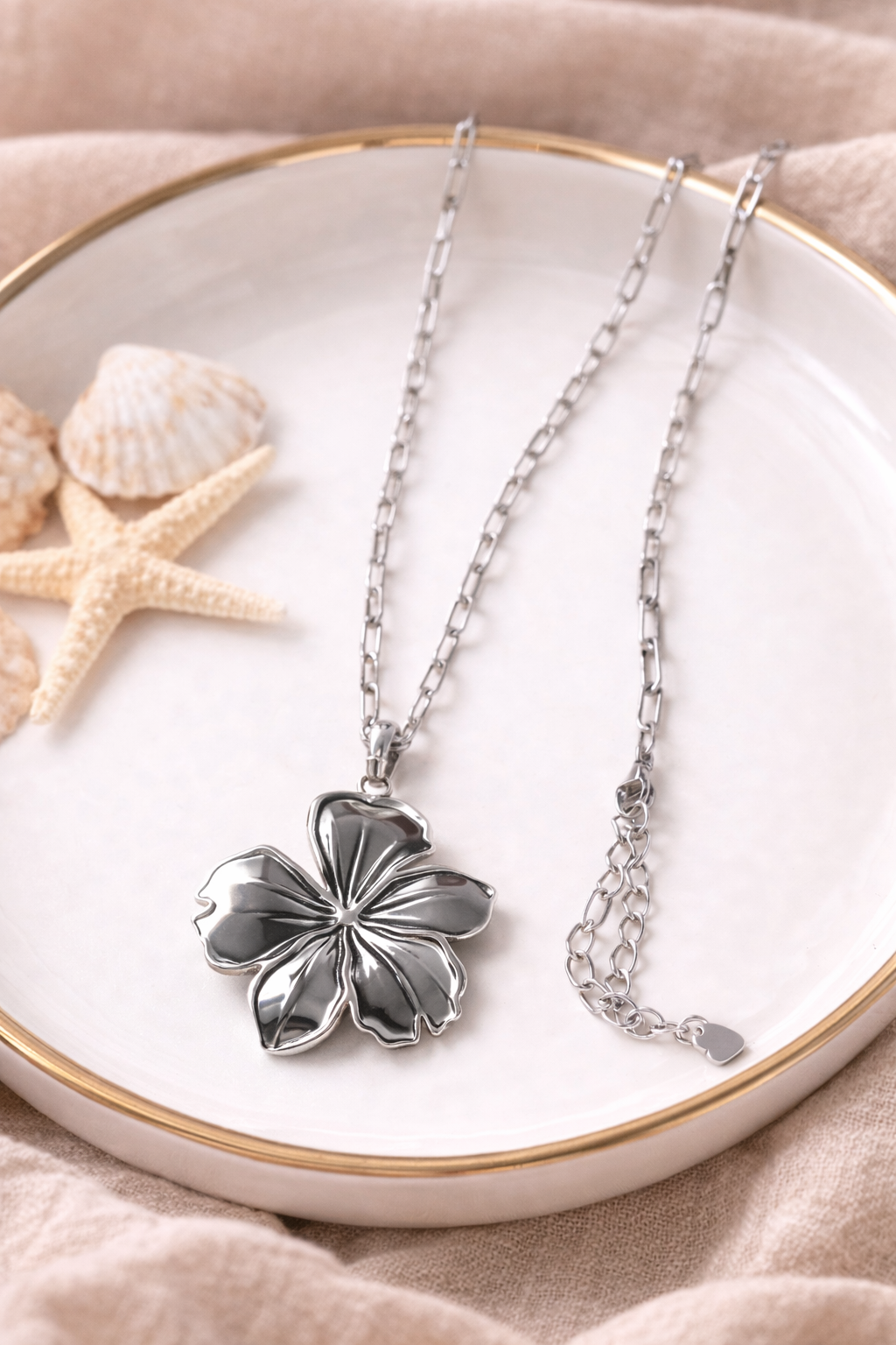 “Gouden ketting met bloem hanger, elegant dames sieraad met luxe en verfijnde uitstraling”gepresenteerd p een schaal.