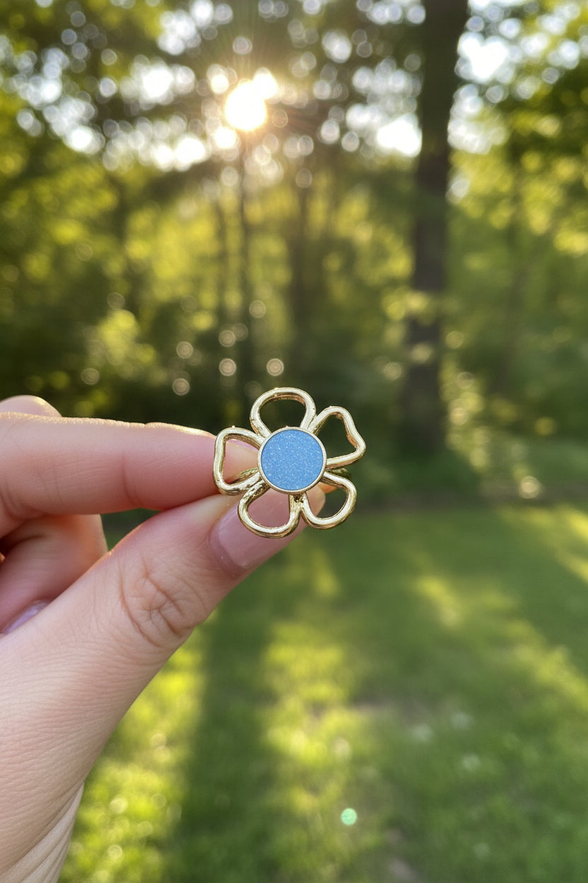 "Productfoto van de verstelbare gouden ring met blauwe steen, focus op de details van de bloemblaadjes."