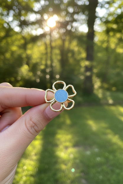 "Productfoto van de verstelbare gouden ring met blauwe steen, focus op de details van de bloemblaadjes."