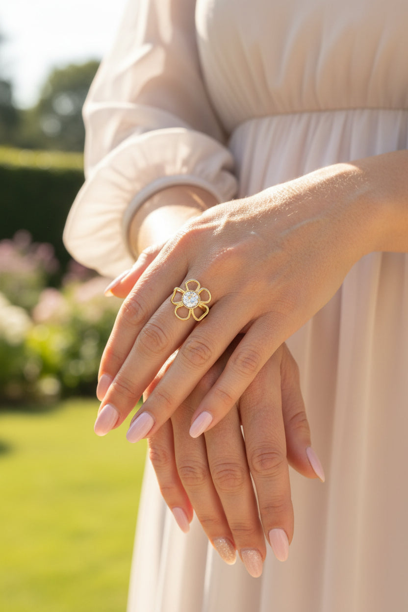Lifestyle foto van de goudkleurige RVS Flower ring met een glinsterende lichte steen, gedragen bij een elegante beige jurk."