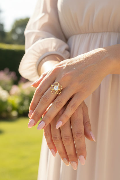 Lifestyle foto van de goudkleurige RVS Flower ring met een glinsterende lichte steen, gedragen bij een elegante beige jurk."