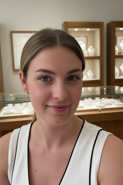 Model draagt Glow Mystic zilveren bloem oorbellen met roze kristallen in een luxe sieradenboetiek setting.