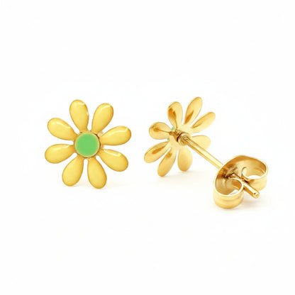 "Een paar goudkleurige Stainless Steel oorknopjes in de vorm van een madeliefje. De bloemetjes zijn 10mm groot en voorzien van een levendige gele emaille kleur met een fris groen centrum. De set wordt getoond op een linnen achtergrond met een klassieke vlindersluiting, wat de duurzaamheid en kwaliteit van het materiaal benadrukt."
