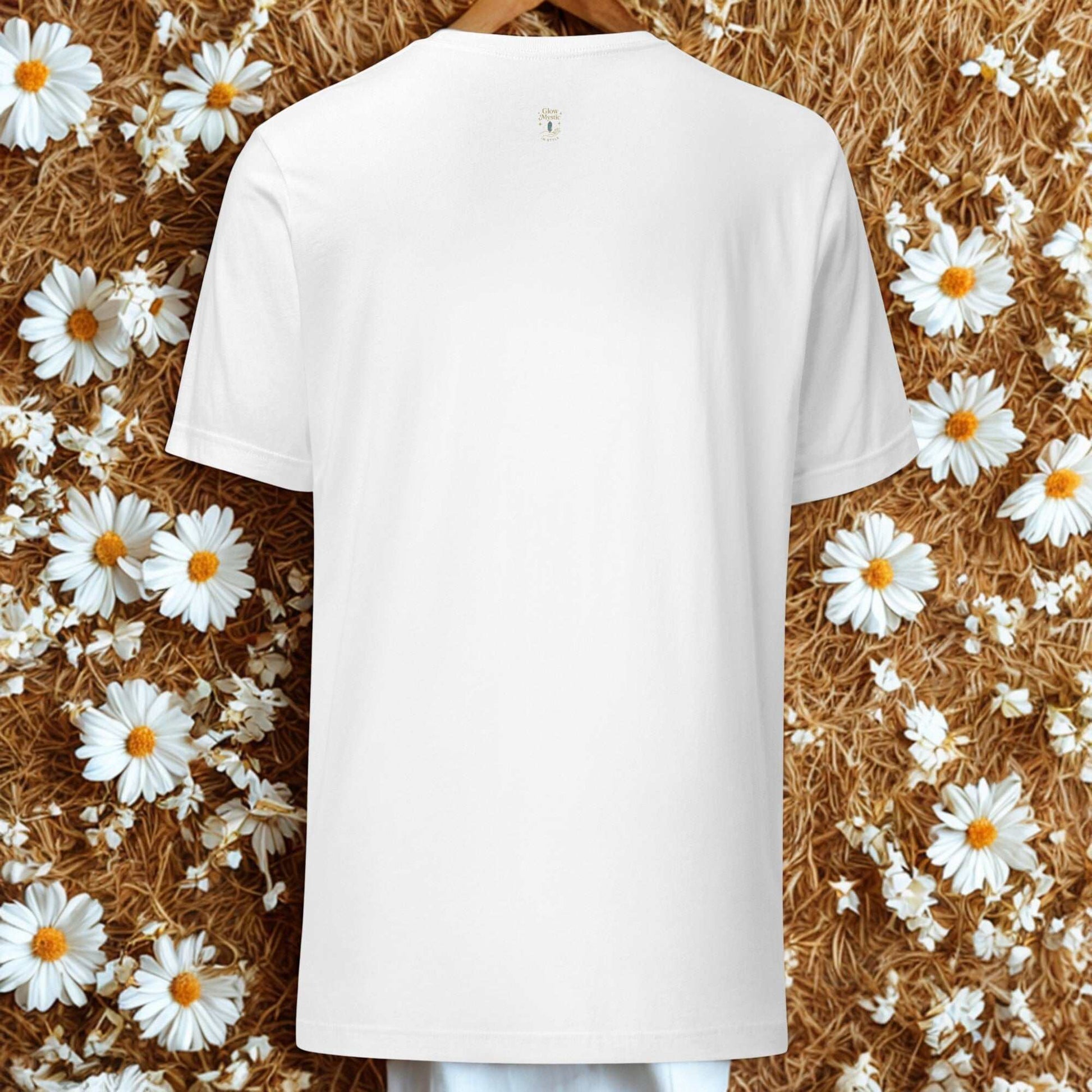 Back view of plain white Celestial Glow Goddess T-Shirt on floral and straw background