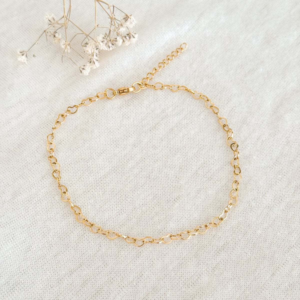 Detail van goudkleurige hartvormige schakels enkelbandje