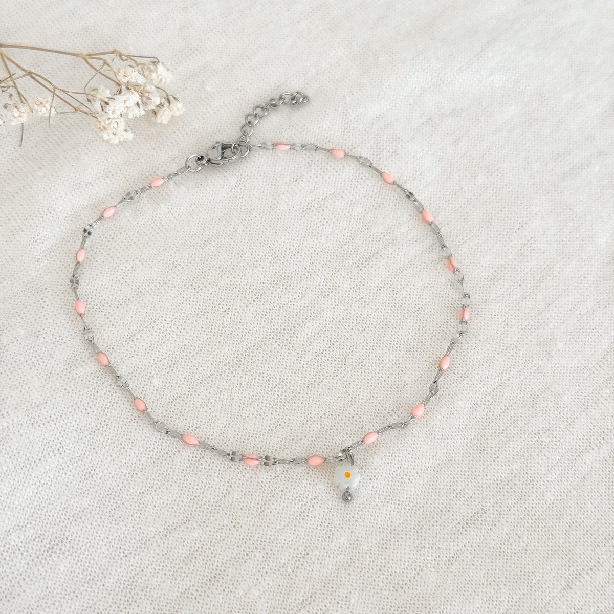 Detail van roze emaille enkelbandje met wit madelief kraaltje