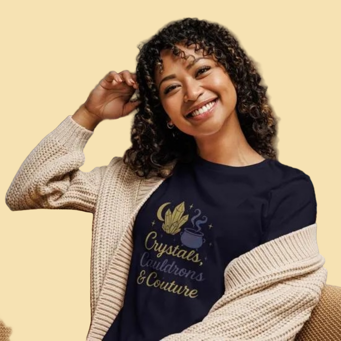 Woman wearing navy Crystals Cauldrons and Couture T Shirt with crystal and cauldron design, cozy beige cardigan indoors