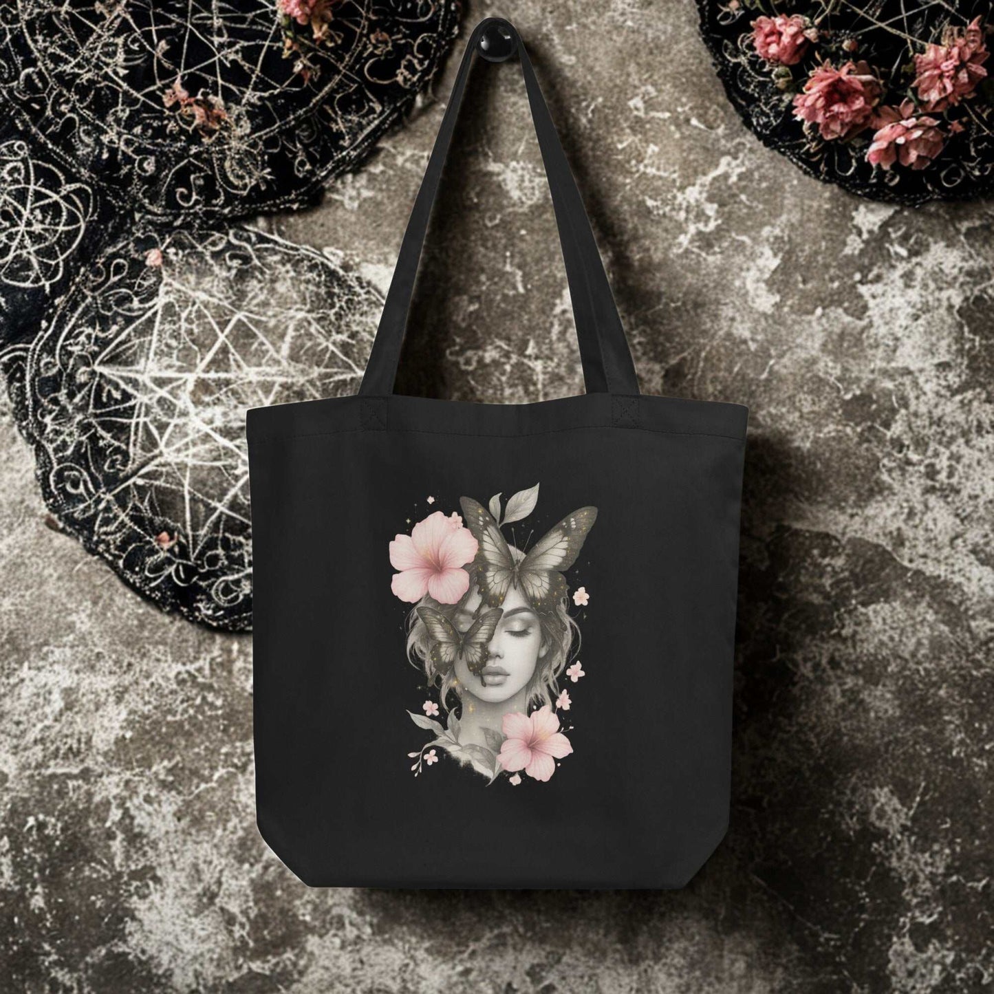Black eco tote bag with artistic floral and butterfly woman design, durable and spacious reusable organic cotton bag.