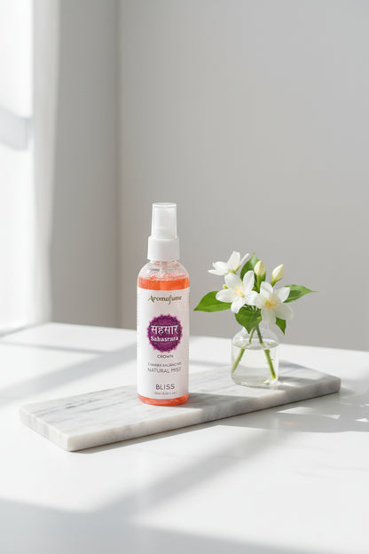 Aromafume 7e Chakra roomspray Sahasrara Crown Bliss 100ml natuurlijke mist flacon - Glow Mystic in Style gepresenteerd op een langwerpige marmeren schaal met een vaasje et witte bloemen ernaast.