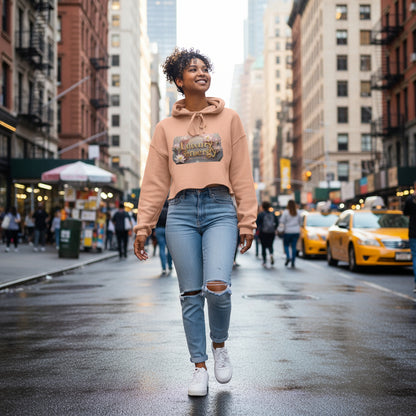 woman wearing Luxury is My Energy Cropped Hoodie in blush pink with floral graphic, paired with black leggings in gym setting
