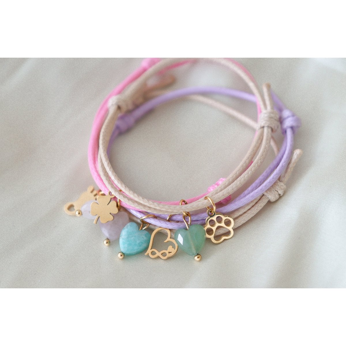 "Sfeerfoto van diverse waxkoord armbandjes bij elkaar gelegd, met focus op de variëteit aan kleuren en bedels.