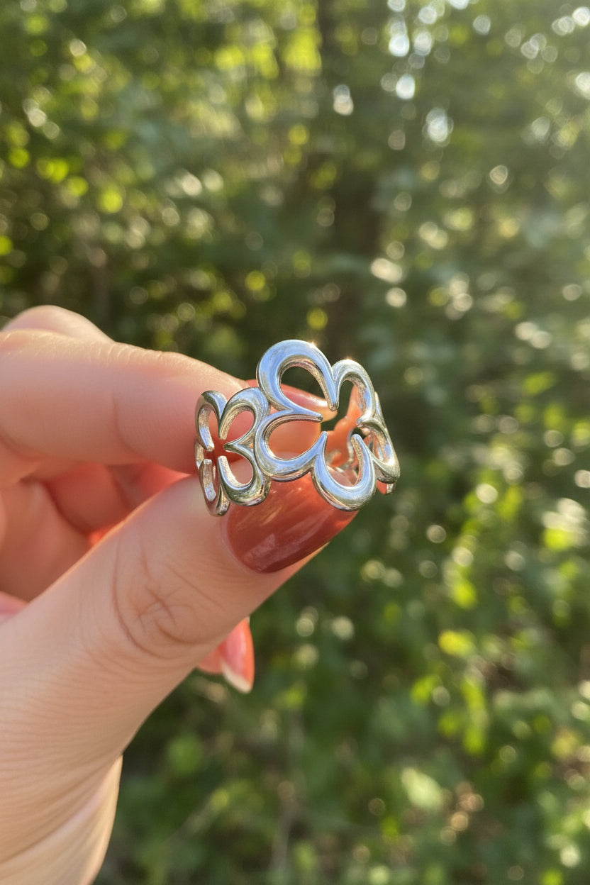 "De Five Flower ring van Glow Mystic in Style, gefotografeerd in het natuurlijke buitenlicht tegen een achtergrond van groene bladeren."