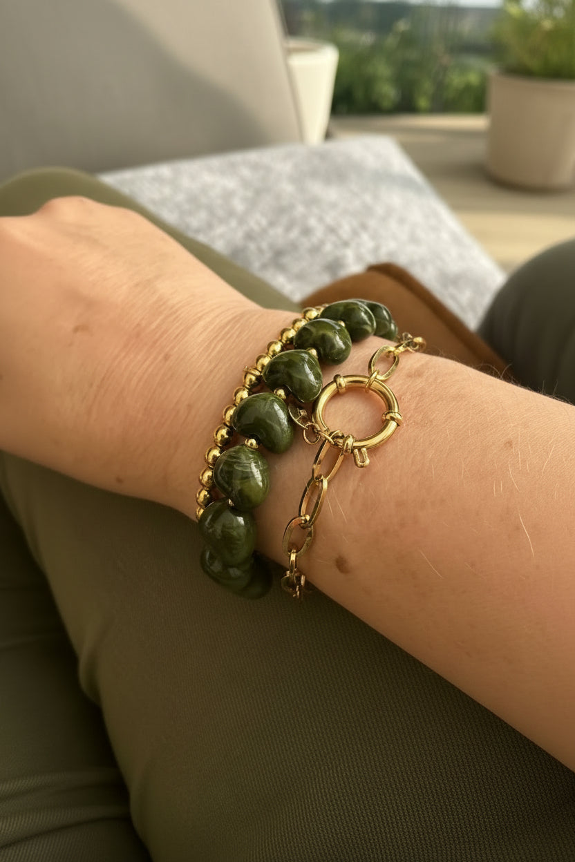Groene hartjesarmband met goudkleurige kralen van stainless steel gedragen om de pols