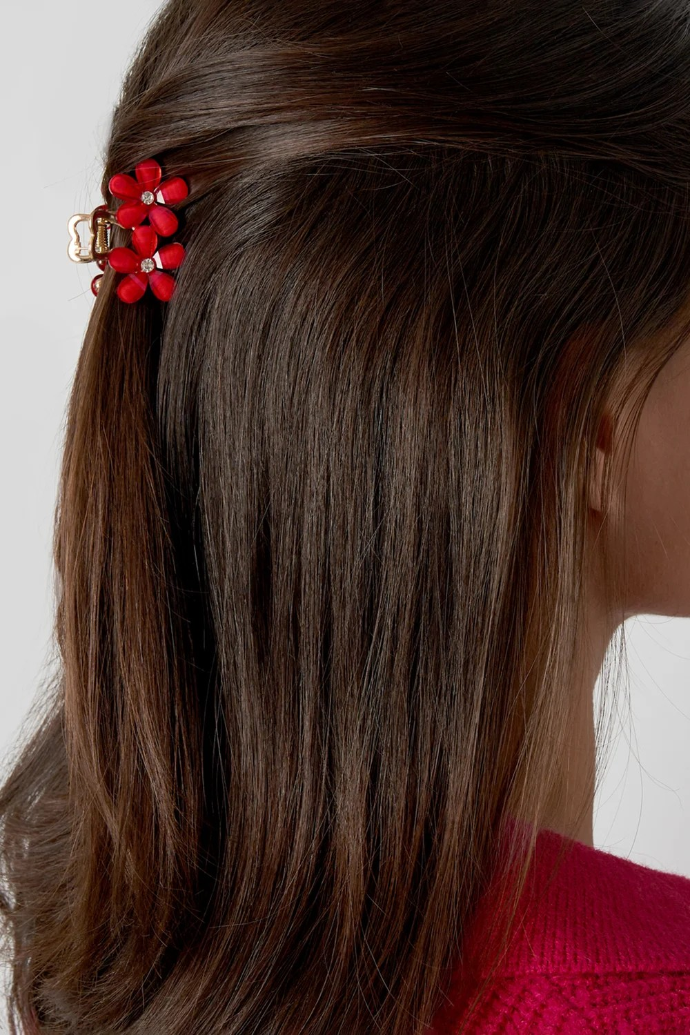 Model draagt kleine gouden haarclip met rode bloemen in half-opgestoken haar