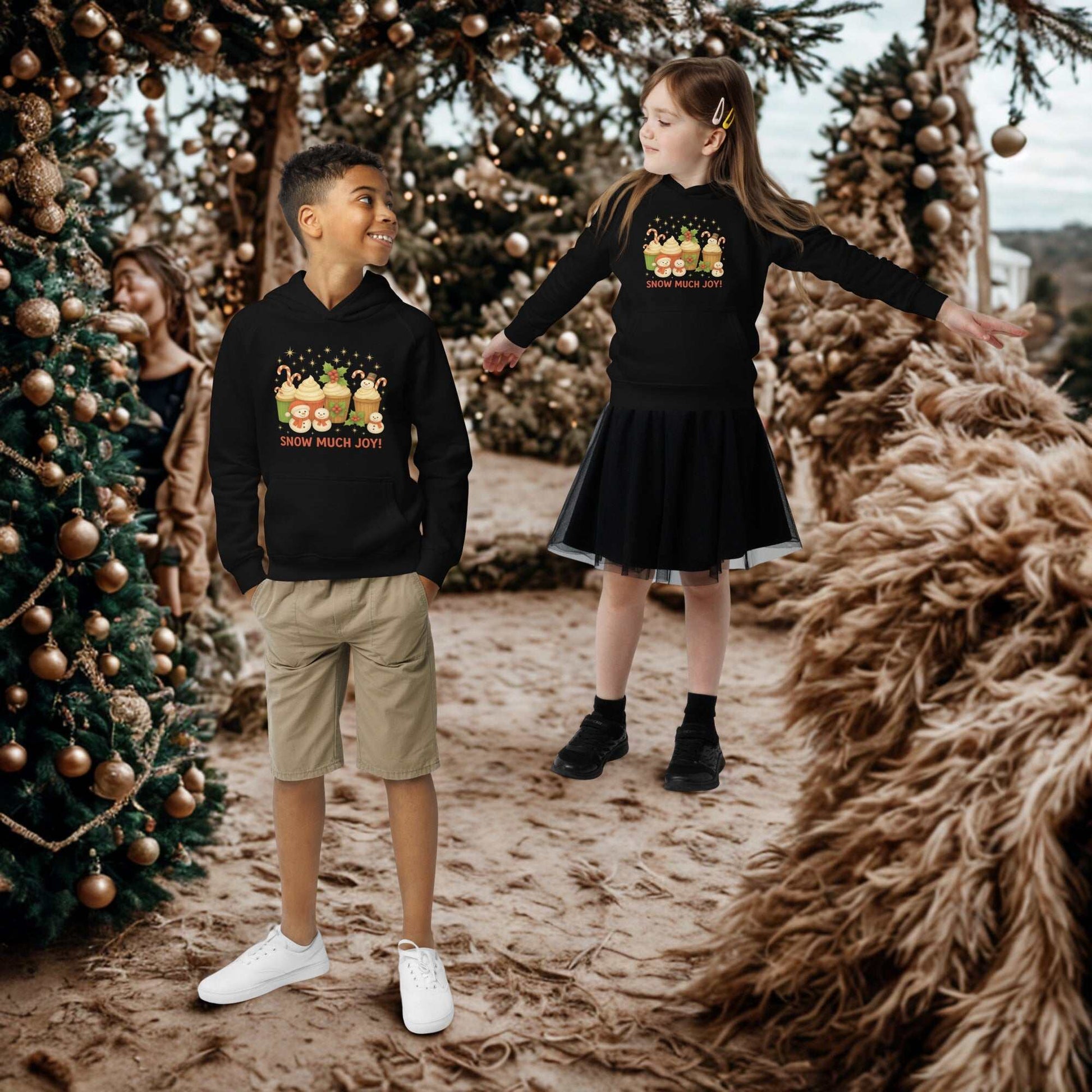 Children wearing black Kids Christmas Hoodies with festive designs standing outdoors near decorated trees
