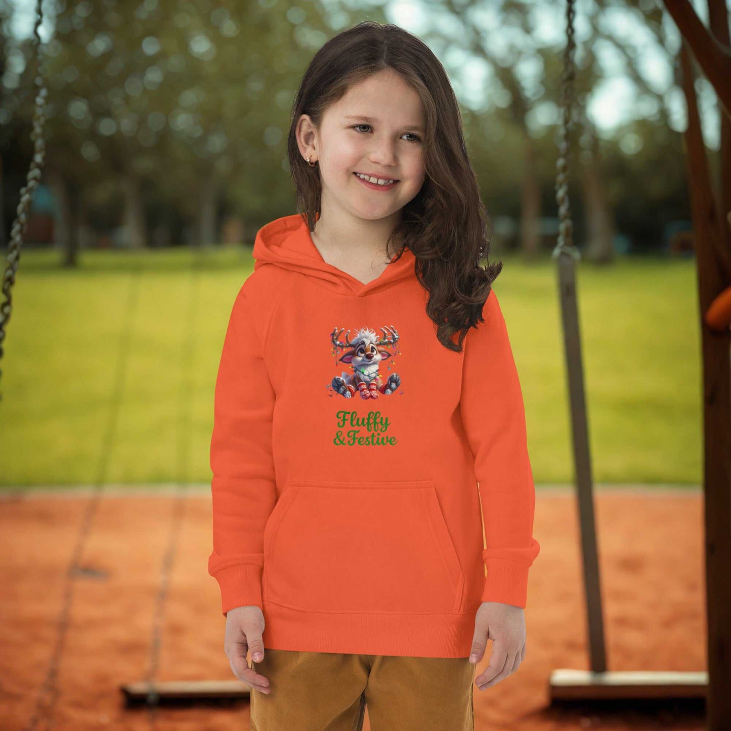 Child wearing orange kids Christmas hoodie with festive reindeer design outdoors on playground