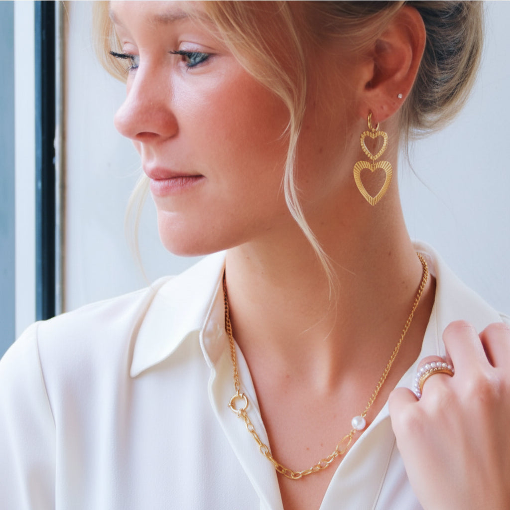 Goudkleurige statement hart oorbellen van 5 cm lang gedragen door model